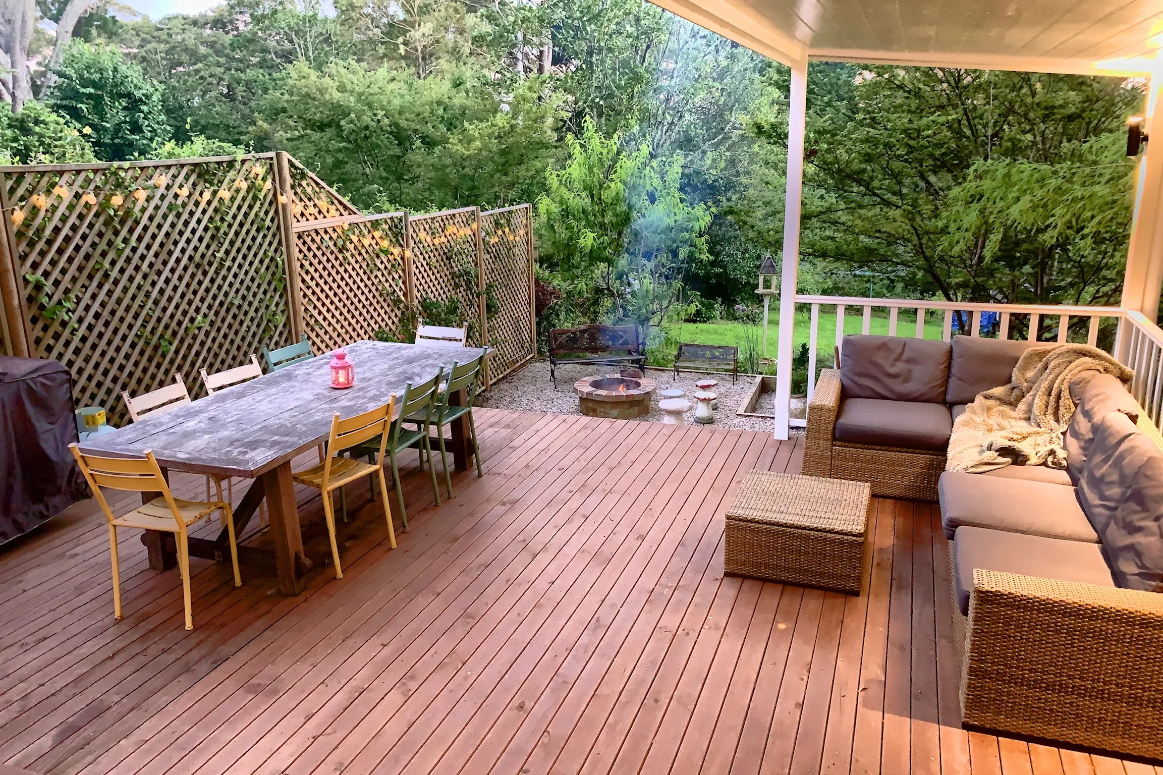 Covered deck with dining table and lounge at dusk