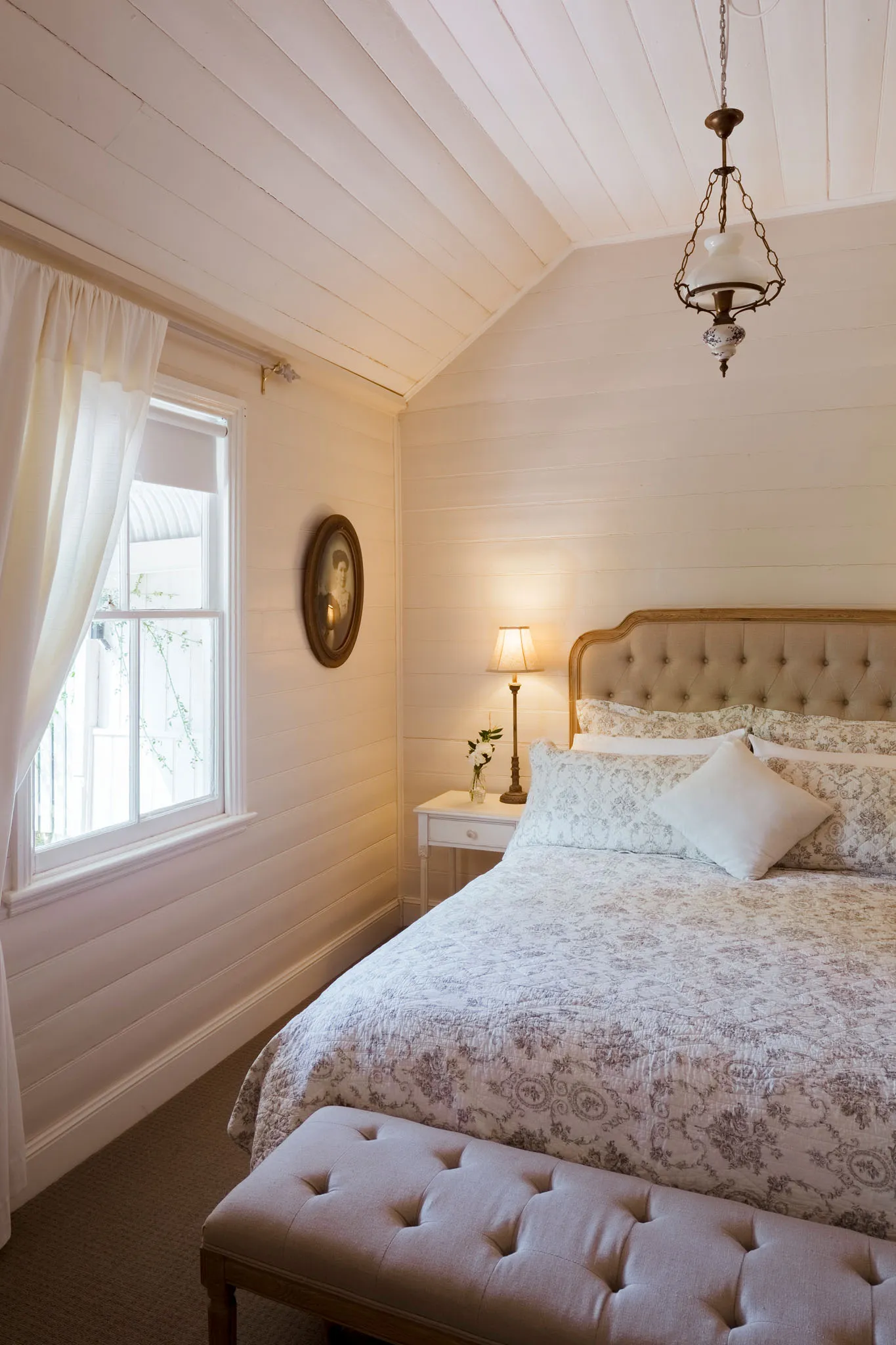 Queen bedroom with window and oval portrait
