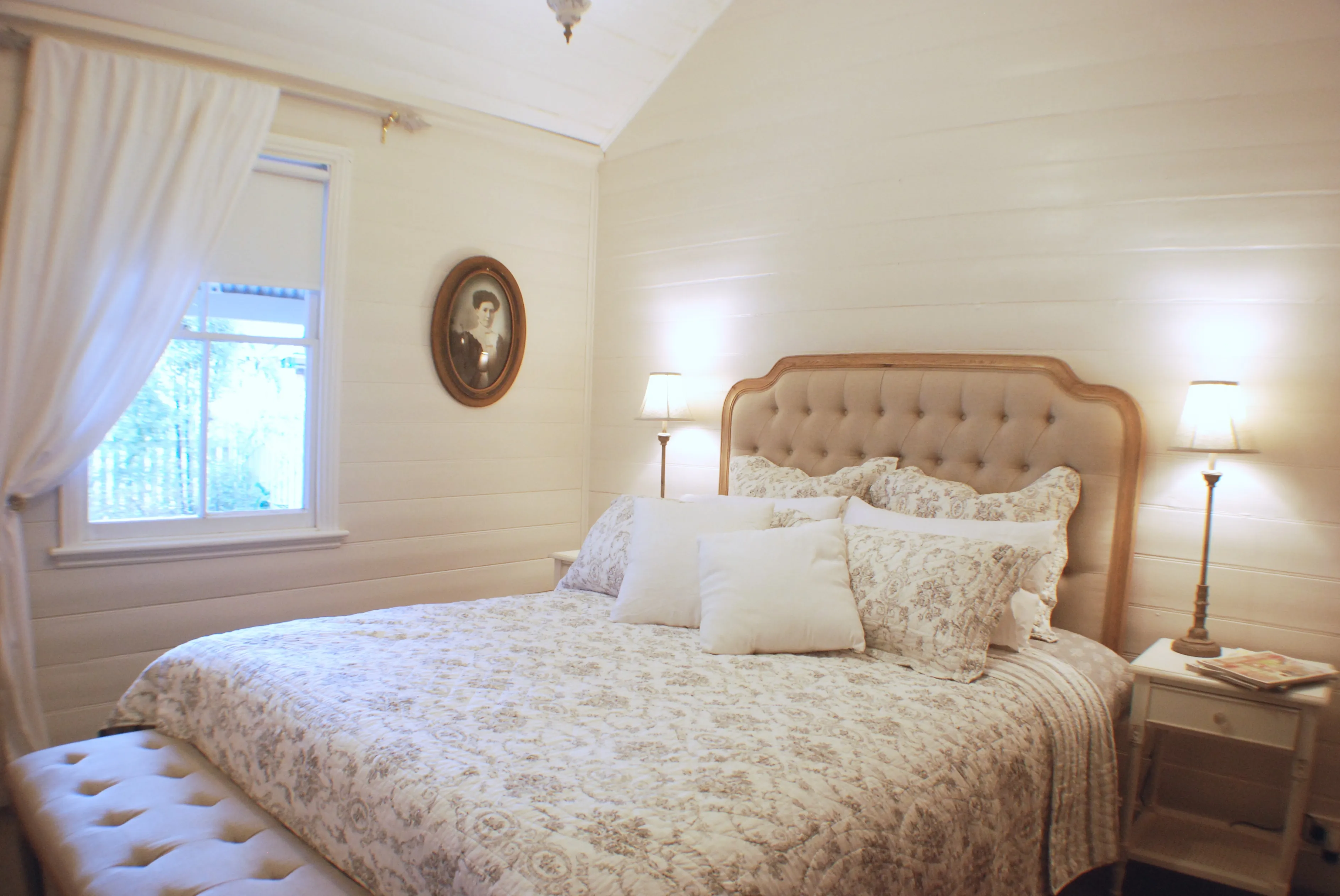 Queen bedroom with tufted linen headboard and period portrait