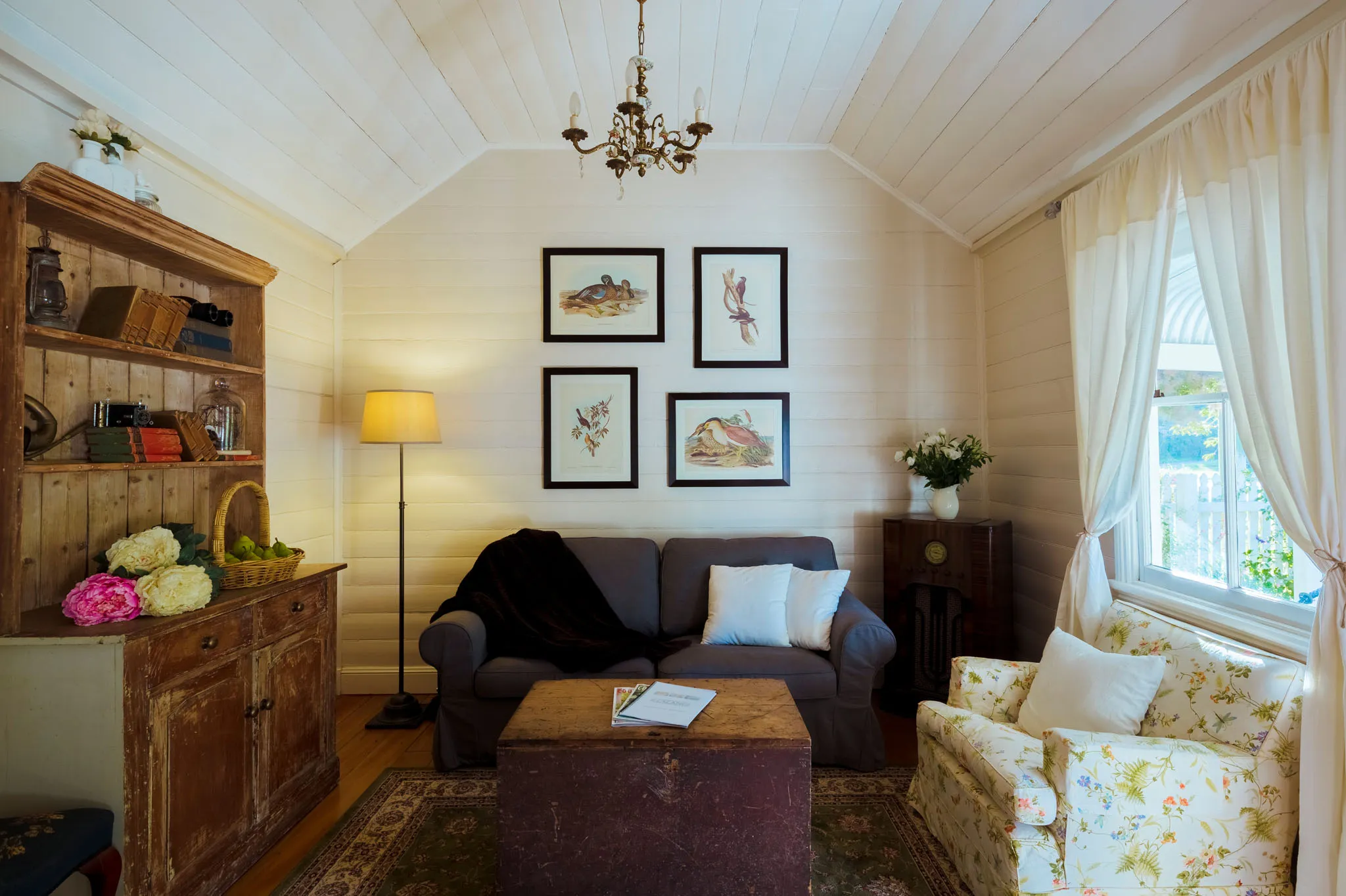 Sun-filled sitting room with antique timber dresser and chandelier